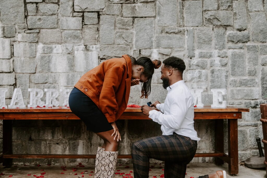 man on one knee proposing to an overwhelmed women