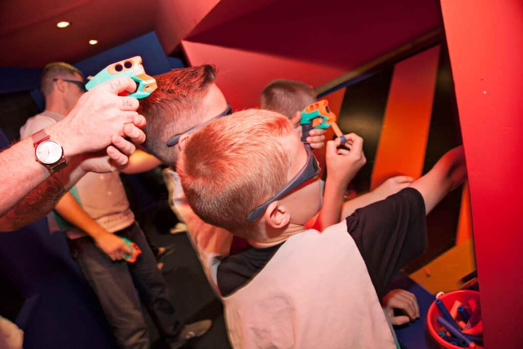 Boys and adults at a Nerf gun shooting range.