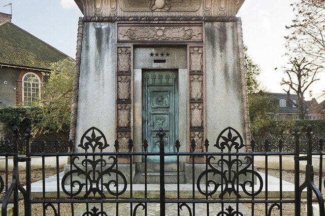 Egyptian Revival Kilmorey Mausoleum behind ornate black iron railings in Twickenham.