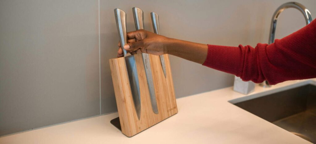 person picking up a knife from a knife rack