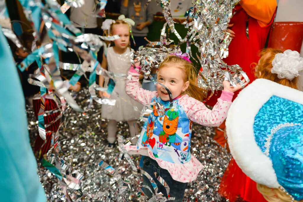 Little girls playing with silver party decoration.