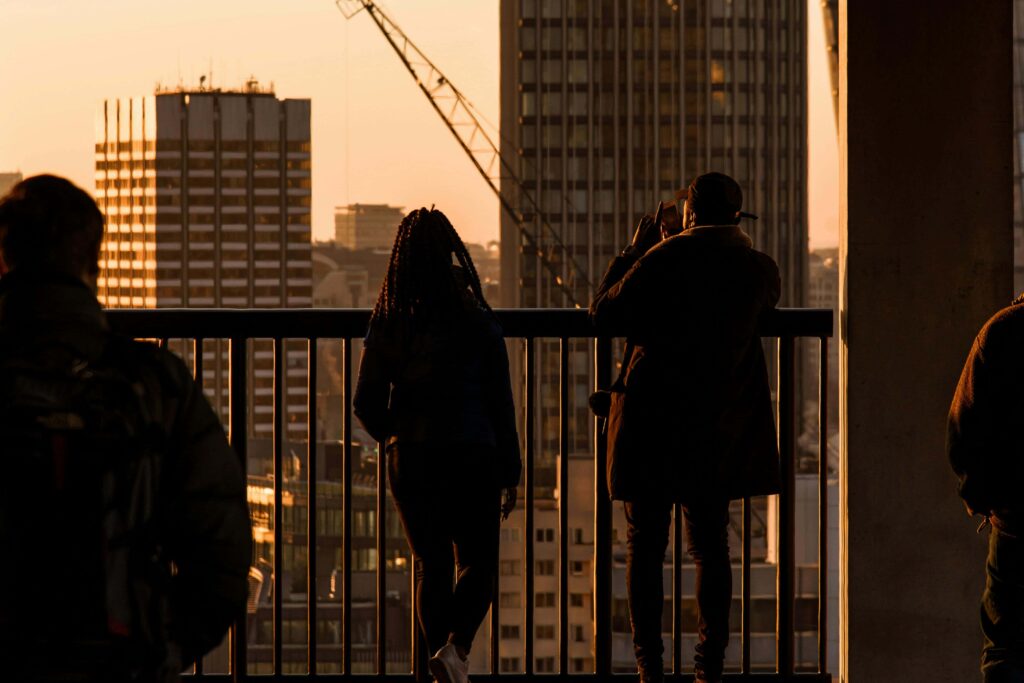 People standing on a rooftop in London watching and photographing the sunset.