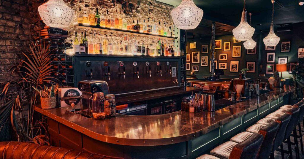 A dimly lit speakeasy bar with high chairs.