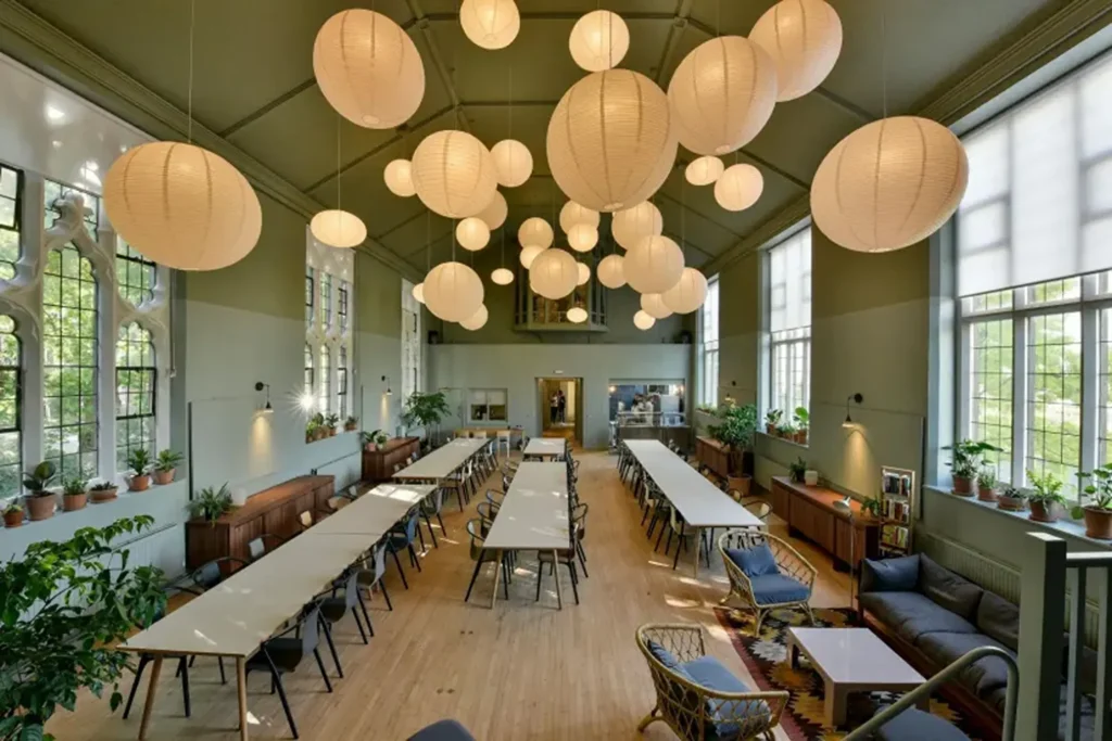 Large event venue with globe-like lamp fixtures, long tables and green walls