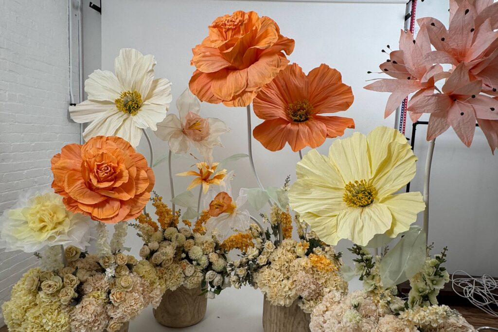 A photo studio with large artificial flowers, decorated for a photo shoot.