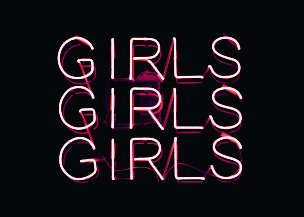 Pink neon sign reading "Girls, Girls, Girls" on a dark background.