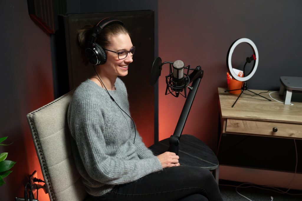 Woman recording a podcast in a studio, sitting in front of a microphone.