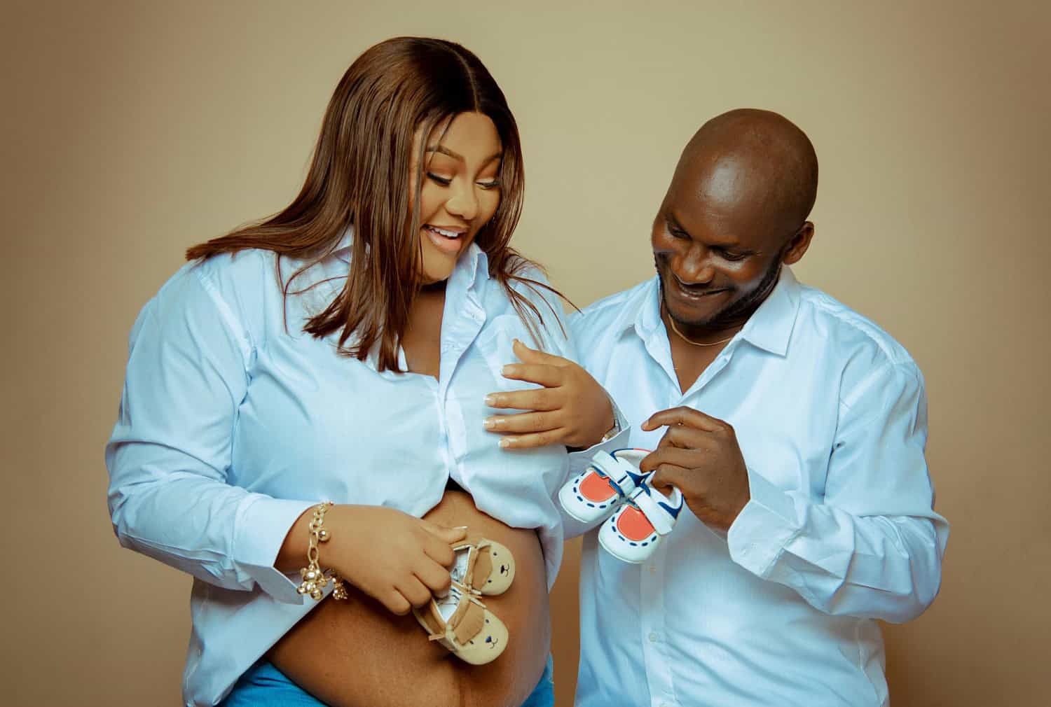 couple holding different coloured baby shoes
