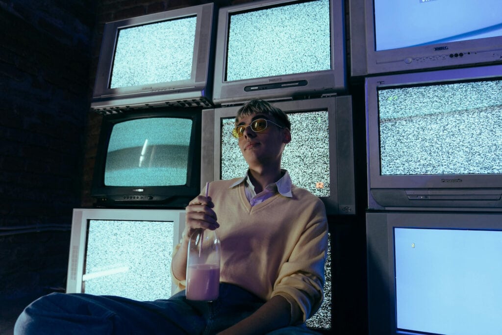 preppy dressed man in front of 80s tvs