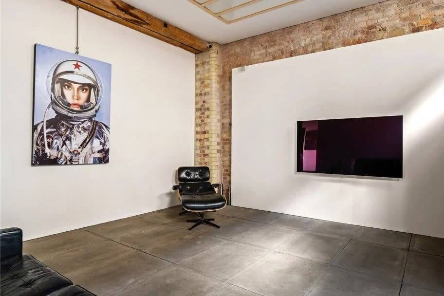 A private screening room or lounge with a TV and a portrait of an astronaut.