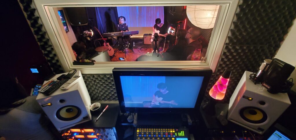 A band recording a song in a professional studio setting.