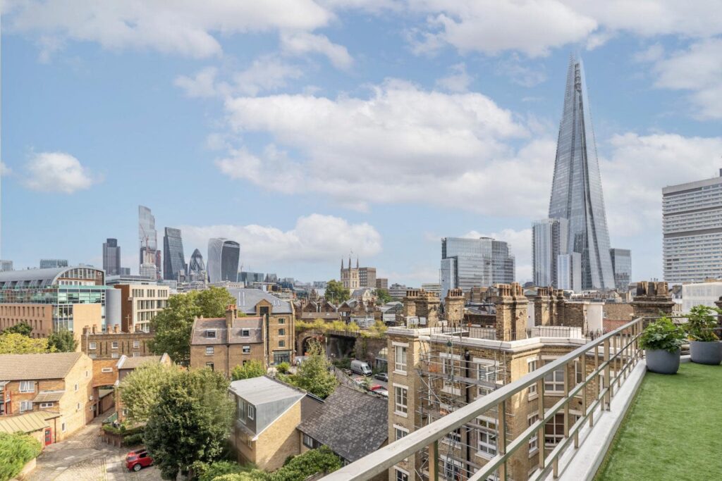 Rooftop rental with artificial grass, city view, and London skyline including The Shard and modern skyscrapers.