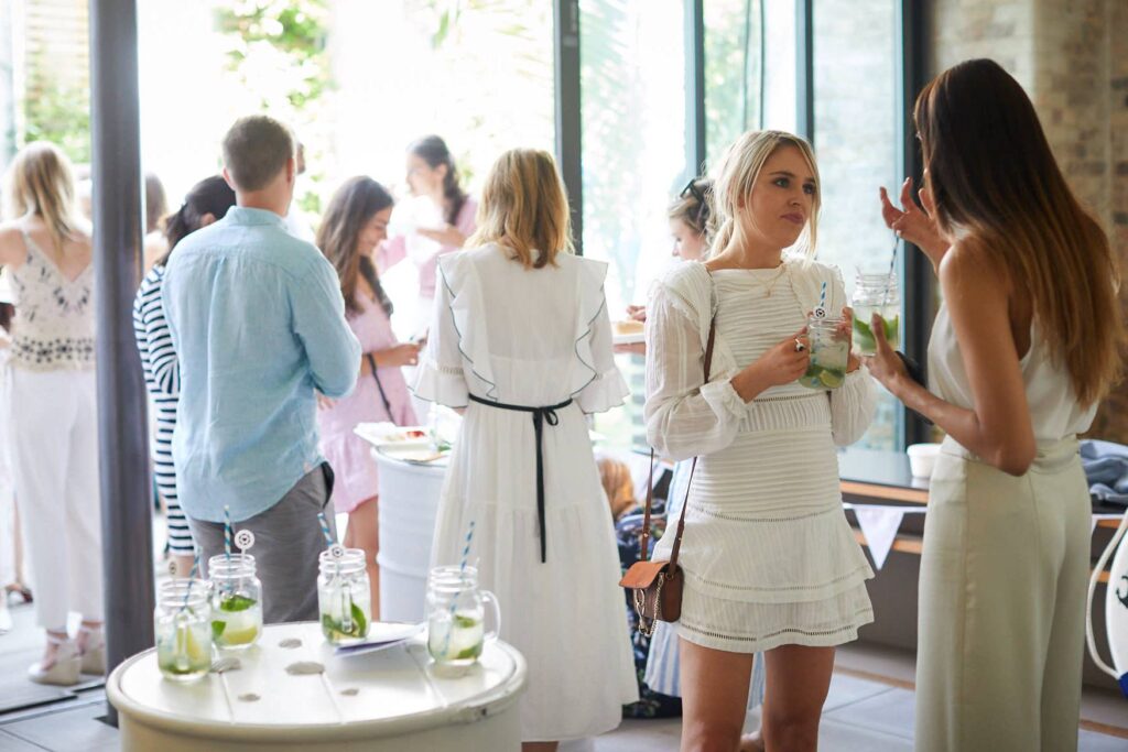 A social gathering over cocktails inside a sunny lounge with doors to the patio in summer.