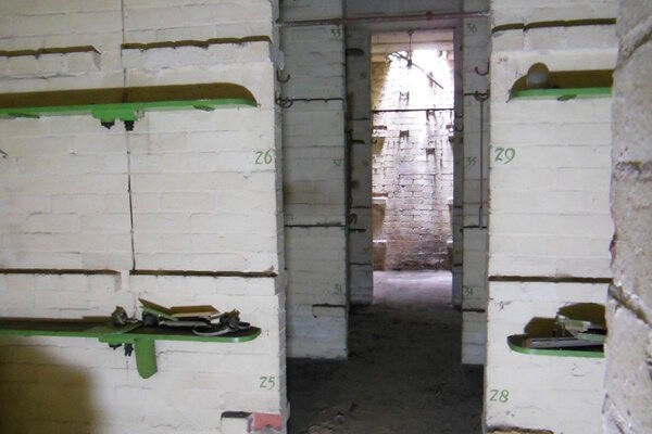 White brick sleeping quarters with numbered wooden bunk slats in St Leonards Court air raid shelter.
