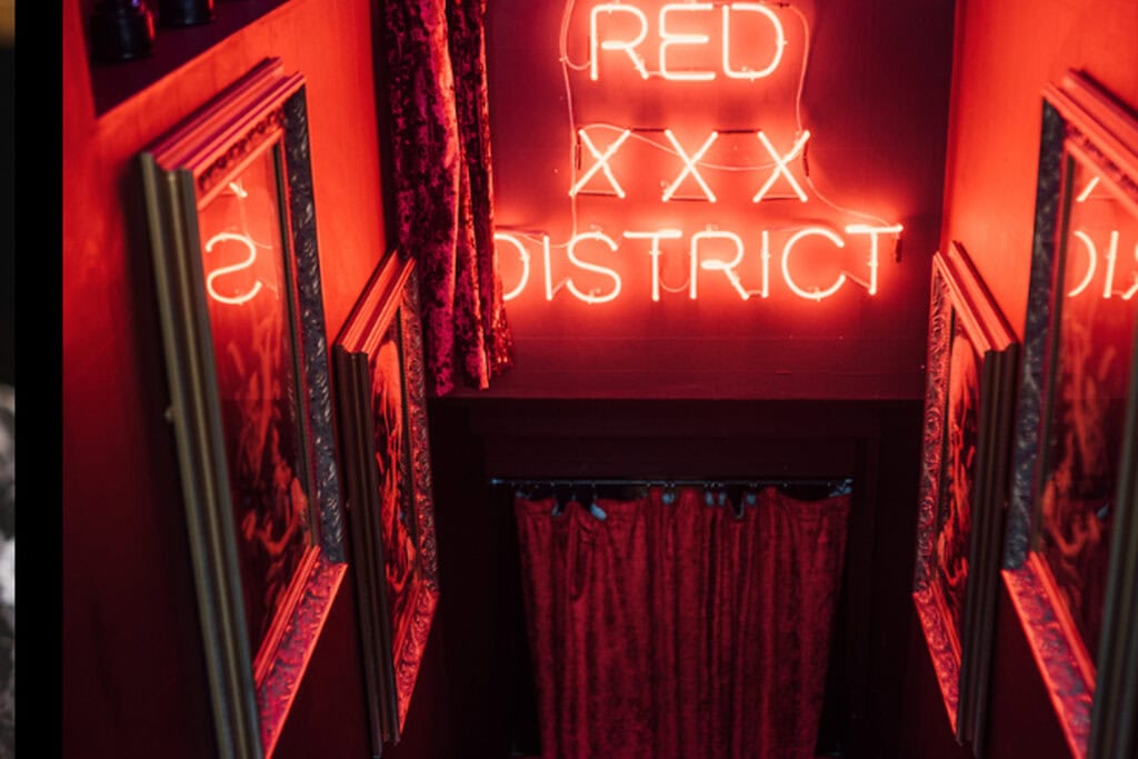 Red-lit stairway and neon entrance inside The Absent Ear speakeasy in Glasgow