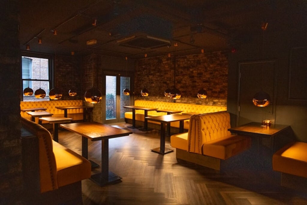Orange leather booths inside The Washhouse hidden cocktail bar in Manchester