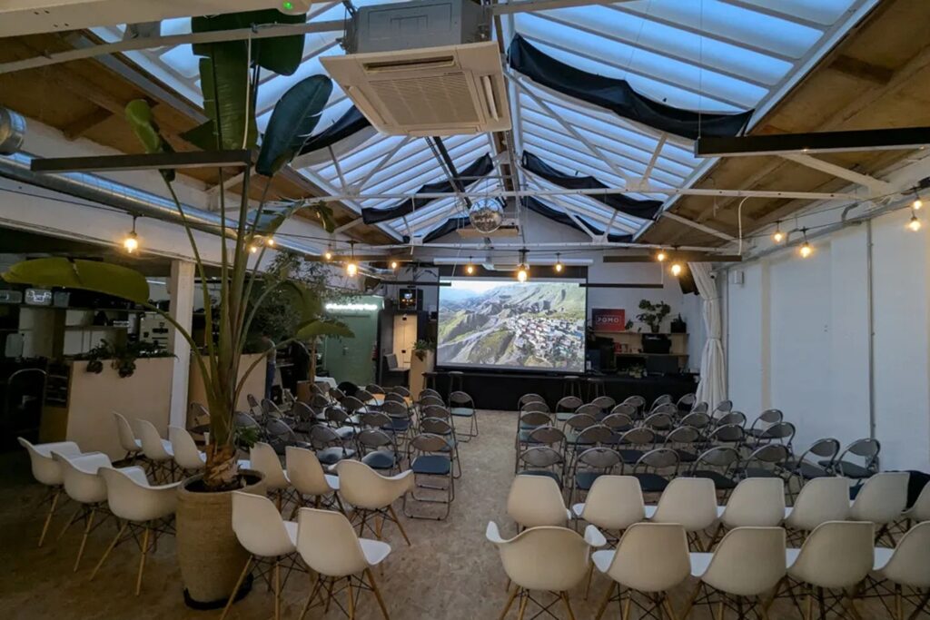 Warehouse venue in London with vaulted glass ceiling, a projector, screen and chairs for a screening.