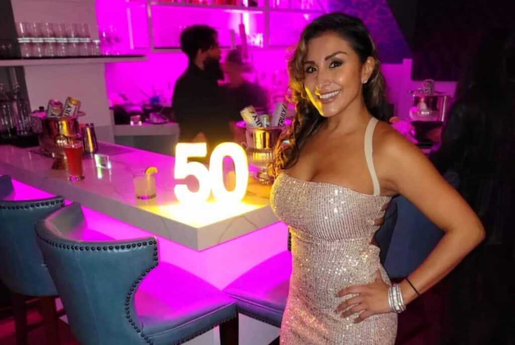 woman standing next to a 50 birthday light at a party