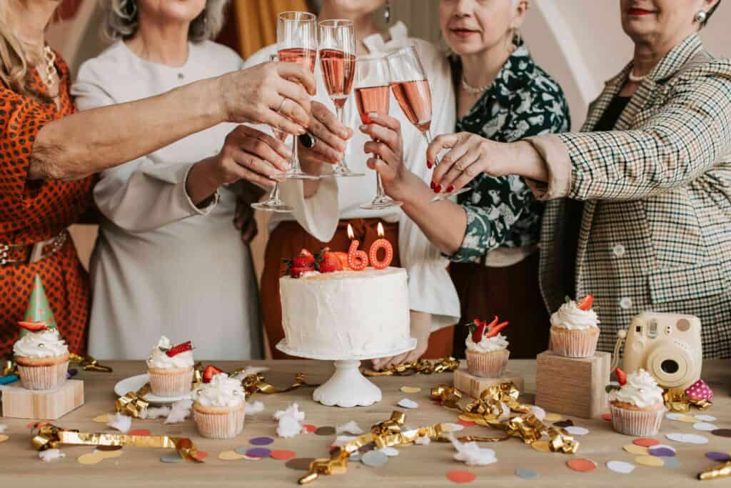 A group of women toast over a 60th birthday cake on the table.